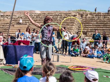 Purim festivalin katılımcı ziyaretçiler Caesarea, İsrail için çemberler ile juggles