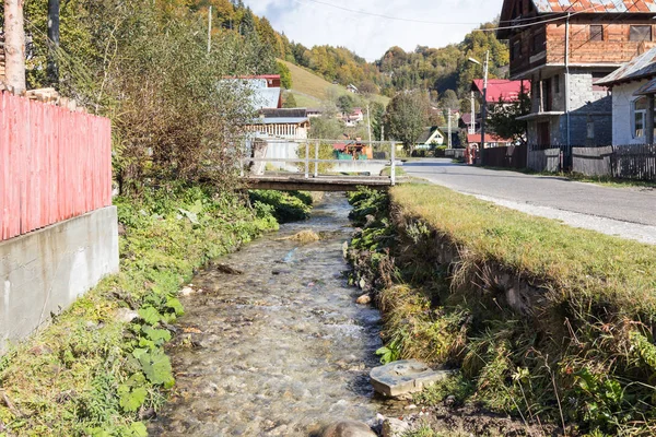 Silnice procházející blízko potoka vesnice nedaleko města Bran v Rumunsku — Stock fotografie