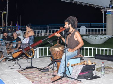 Genç bir adam büyük bir boru akşam şehir Nahariya, İsrail waterfront üzerinde çalış