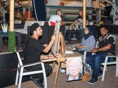 Sokak ressam akşamları bir sandalyeye oturur ve onun için Nahariya, İsrail'de poz veriyor bir çift bir kalem çizer.