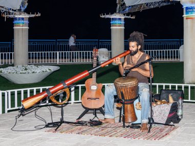 Genç bir adam büyük bir boru akşam şehir Nahariya, İsrail waterfront üzerinde çalış