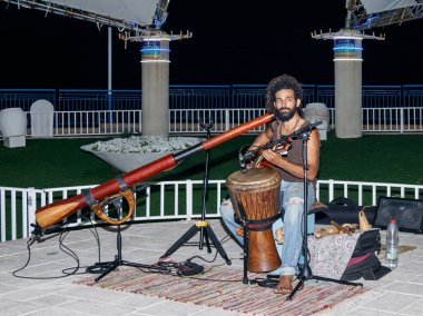 Genç bir adam bir gitar çalar akşam sahildeki şehir Nahariya, İsrail