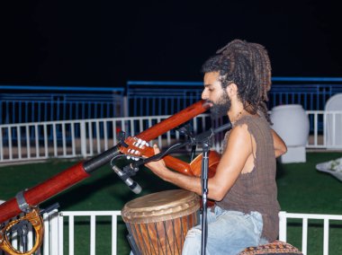 Bir genç adam bir gitar ve büyük bir boru akşam şehir Nahariya, İsrail'de sahildeki çalış