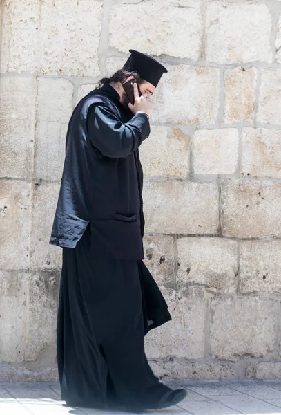 Священник стоит и разговаривает по мобильному телефону в старом городе Иерусалима, Израиль . — стоковое фото