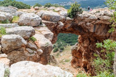 Turistler dikilip Keshet Mağarası 'na bakıyorlar. İsrail' in Shlomi kenti yakınlarında geniş manzaralı sığ bir mağaranın kalıntılarını kaplayan antik doğal kireçtaşı kemeri.
