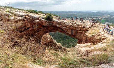 Turistler dikilip Keshet Mağarası 'na bakıyorlar. İsrail' in Shlomi kenti yakınlarında geniş manzaralı sığ bir mağaranın kalıntılarını kaplayan antik doğal kireçtaşı kemeri.