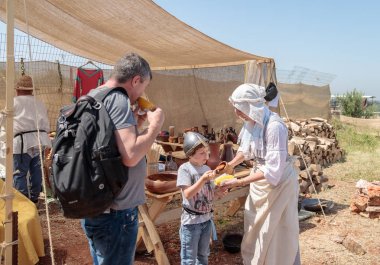 Şövalye festivalin bir katılımcısı cook haşlanmış Mısır İsrail Goren parkta ziyaretçi yardımcı olur.