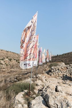Flags with the names of all the tribes of Israe lon the archaeological excavations of the Ancient Shiloh archaeological site in Samaria region in Benjamin district, Israel clipart