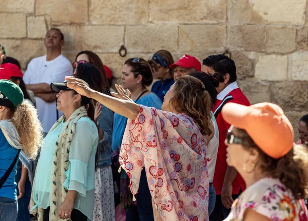 Believer lifts her hands to heaven during group prayer in the courtyard of the Chapel of the Ascension on Mount Eleon - Mount of Olives in East Jerusalem in Israel