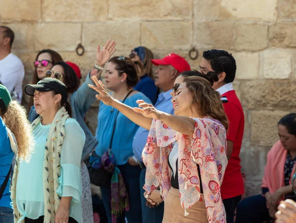 Верующая поднимает руки к небу во время групповой молитвы во дворе часовни Вознесения на горе Элеон - Масличной горе в Восточном Иерусалиме в Израиле — стоковое фото
