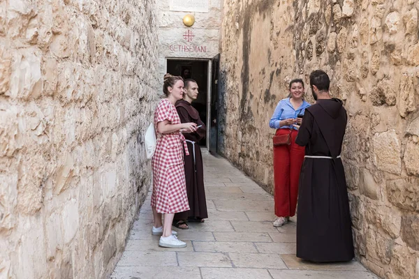 Dwóch młodych mnichów wstaje i rozmawia z dwiema młodymi dziewczynami przy wejściu do Groty Getsemane pieszo na Górze Eleon - Górze Oliwnej we Wschodniej Jerozolimie w Izraelu — Zdjęcie stockowe