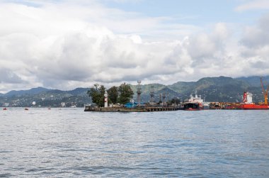 Yağmurlu bir günde Gürcistan 'ın başkenti olan Batumi şehrinin Karadeniz seti üzerinde bir deniz feneri bulunan kargo limanı.