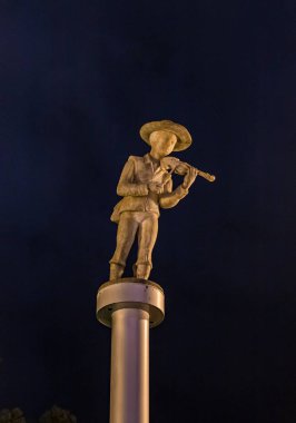 Gürcistan 'ın başkenti Adjara' daki Batumi Bulvarı Çeşmeleri 'nde yüksek bir sütunun üzerinde duran bir kemancının gece manzarası.