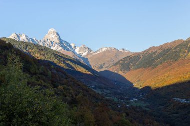 Dağların panoramik manzarası ve kar altında Ushguli zirvesi, Gürcistan 'ın dağlık kesiminde, gün batımında görülebilir.