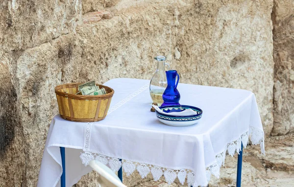 Une cruche d'eau bénite, une cruche d'huile et un panier de dons sont sur la table lors d'une prière collective à Emmaüs Nicopolis — Photo