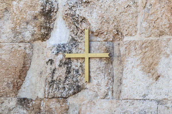 Ένας μεγάλος επίχρυσος σταυρός κρεμασμένος στον τοίχο πάνω στα ερείπια βυζαντινού εκκλησιαστικού συγκροτήματος στο έδαφος του Εμμαούς Νικόπολης — Φωτογραφία Αρχείου