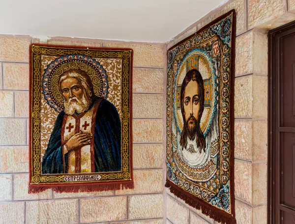 Alfombras en los rostros de Jesús y San Serafín cuelgan de la pared de la iglesia de San Nicolás en Bay Jala - un suburbio de Belén en Palestina — Foto de Stock