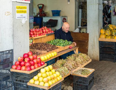 Bir satıcı, Gürcistan 'ın Kutaisi bölgesindeki bir markette meyve tablasının yanında oturuyor.