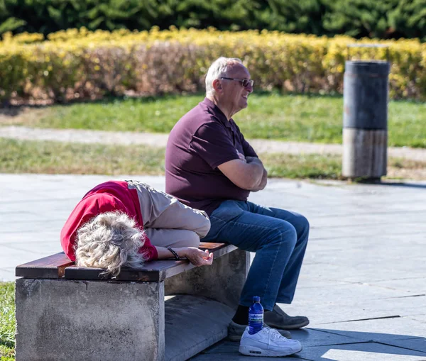 Turistas ancianos cansados descansan en un banco en Rike Park en la parte antigua de la ciudad de Tiflis en Georgia — Foto de Stock