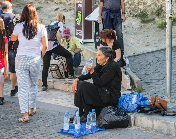 Una anciana se sienta y vende pequeñas botellas de agua potable en la colina de Narikhala en la ciudad de Tiflis, Georgia — Foto de Stock