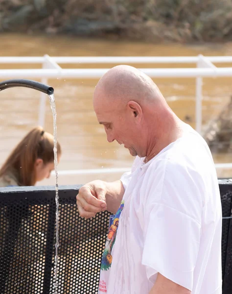 Gläubige, die zum Epiphaniasritus kommen, kreuzen sich selbst und verwenden Weihwasser zur Waschung aus dem jordanischen Fluss an der Taufstätte von Jesus Christus in der Nähe von Jericho in Israel — Stockfoto