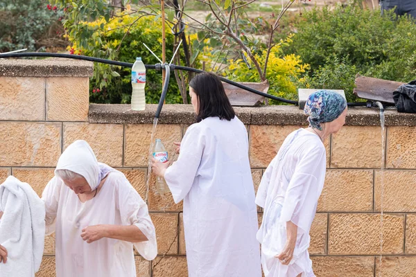 Los creyentes que llegan al Rito de la Epifanía recogen agua bendita en una botella del río Jordán en el Sitio Bautismal de Jesucristo cerca de Jericó en Israel — Foto de Stock