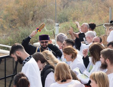 Rahip, İsrail 'deki Jericho yakınlarındaki Ürdün Nehri' ndeki İsa Mesih 'in Vaftiz Alanına inananların üzerine kutsal su serpiyor.