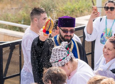 Rahip, İsrail 'deki Jericho yakınlarındaki Ürdün Nehri' ndeki İsa Mesih 'in Vaftiz Alanına inananların üzerine kutsal su serpiyor.