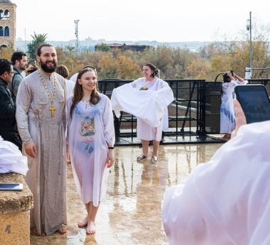 Jericho, Israel, January 18, 2020 : Believers happily take pictures after use Holy Water for ablution from the Jordan River on the Baptismal Site of Jesus Christ near Jericho in Israel