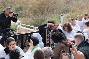 Jericho, İsrail, 18 Ocak 2020: Rahip, İsrail 'deki Jericho yakınlarındaki Ürdün Nehri' ndeki İsa Mesih 'in Vaftiz Alanına inananlar üzerine kutsal su serpti