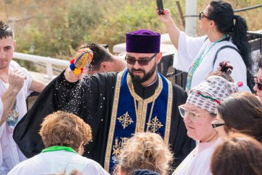 Jericho, İsrail, 18 Ocak 2020: Rahip, İsrail 'deki Jericho yakınlarındaki Ürdün Nehri' ndeki İsa Mesih 'in Vaftiz Alanına inananlar üzerine kutsal su serpti