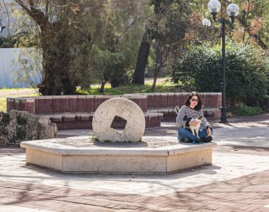 Tel Aviv-Yafo, Israel, February 01, 2020 : A young woman sidin with a cat on the square in front of the Jaffa Theater on Yafo Embankment in old Yafo in Israel