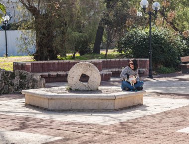 Tel Aviv-Yafo, Israel, February 01, 2020 : A young woman sidin with a cat on the square in front of the Jaffa Theater on Yafo Embankment in old Yafo in Israel
