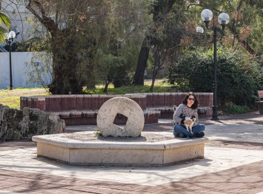 Tel Aviv-Yafo, Israel, February 01, 2020 : A young woman sidin with a cat on the square in front of the Jaffa Theater on Yafo Embankment in old Yafo in Israel