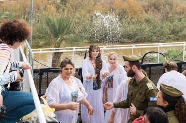 Jericho, İsrail, 18 Ocak 2020: Müminler Ürdün Nehri 'nden İsrail' in Jericho yakınlarındaki Ürdün Nehri 'ndeki İsa' nın Vaftiz Alanına geçenler üzerine kutsal su serpiyorlar.