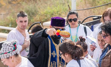 Jericho, İsrail, 18 Ocak 2020: Rahip, İsrail 'deki Jericho yakınlarındaki Ürdün Nehri' ndeki İsa Mesih 'in Vaftiz Alanına inananlar üzerine kutsal su serpti