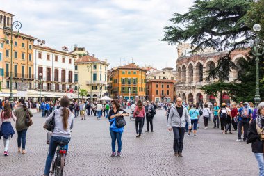 Verona, İtalya, 26 Eylül 2015: Bulutlu bir günde Piazza Sütyen Meydanı 'nda yürüyen turistler, Arena' yı inceleyin ve İtalya 'nın Verona kentindeki arka planında fotoğraf çekin.