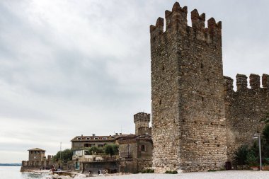 Sirmione, İtalya, 01 Ekim 2015: Kuzey İtalya 'nın Lombardy kentindeki Sirmione kasabasındaki Castello Scaligero kalesinin önündeki köşe kulesiyle kale duvarının bir parçası