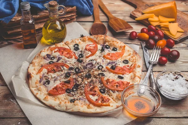 Pizza Margarita on thin crust. Food composition on a wooden background. Mediterranean traditional cuisine. Easy vintage toning