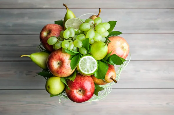 A bouquet of fruits. Apples, grapes and pears on a wooden background. Top view