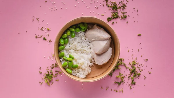 Food banner. Pork with sweet sauce, rice, green beans in a round cardboard bowl on a pink background. Healty Asian cuisine. Top view. Copy space.