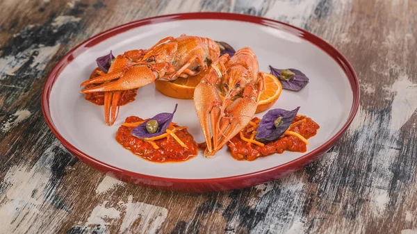 Food banner. Boiled crayfish. Delicacy with chili pepper sauce, orange, zest, basil and capers on a plate. Haute cuisine