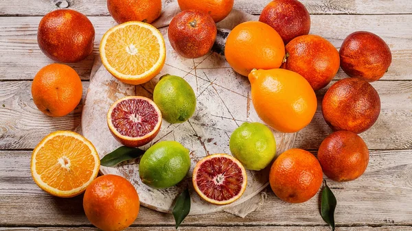 Food banner format. Juicy red oranges, lemons and limes on a wooden table. Seasonal Citrus Fruits