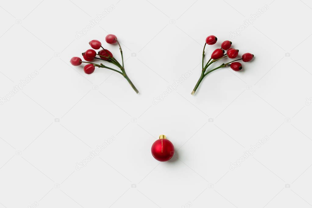 Reindeer face made of Christmas decorations, holly berries and pine branches. Minimal  concept. Flat lay