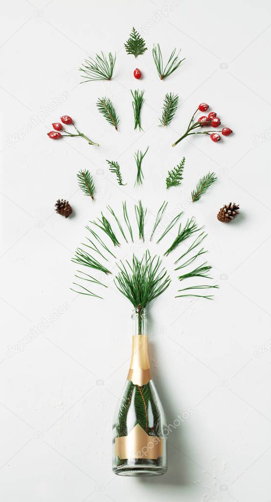 Champagne bottle with winter splash foliage on white background. Flat lay. Party concept.