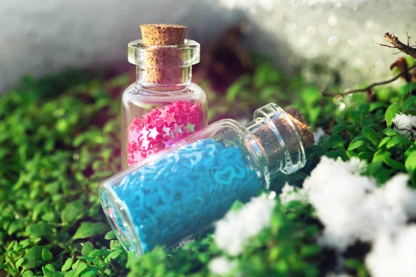 Duas garrafas de vidro com estrelas roxas e corações azuis na floresta . — Fotografia de Stock