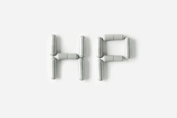 Pillole bianche capsule a forma di parola HP. Concetto vita isolato . — Foto Stock