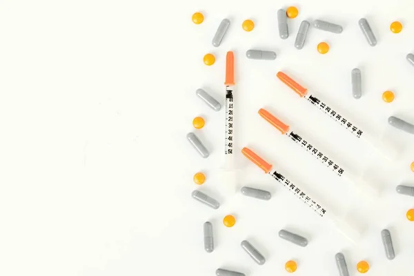 Seringa de insulina, comprimidos e cápsulas sobre metade do fundo branco . — Fotografia de Stock