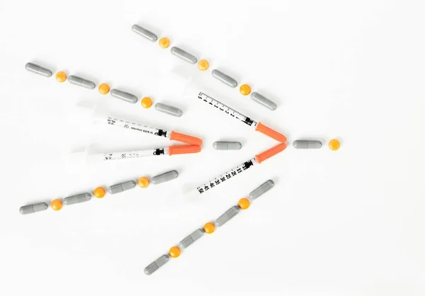 Jeringa de insulina, pastillas y cápsulas en forma de flecha derecha — Foto de Stock
