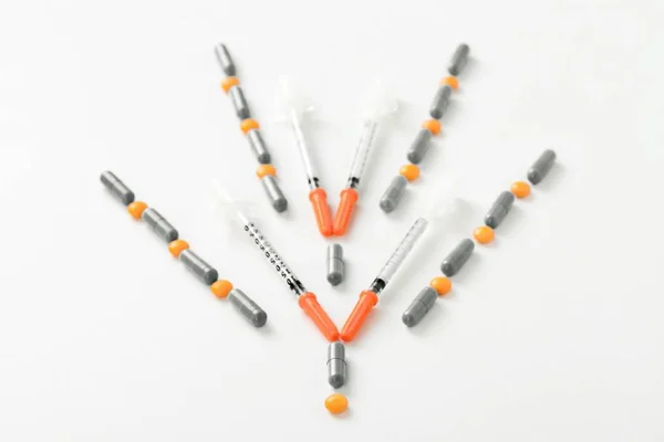 Инсулиновый шприц, таблетки и капсулы в форме стрелки вниз — стоковое фото